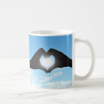 Hände in der Herz-Form-Silhouette auf blauem Himme Kaffeetassen