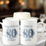 80. Geburtstag - 80 Jahre Blumennummer Porzellantasse<br><div class="desc">Tasse zum 80. Geburtstag, mit vollständig bearbeitbaren Formulierungen, um nach Ihren Wünschen zu personalisieren, wie zum Beispiel "Happy Geburtday [Name]" und/oder "Beifall zu 80 Jahren". Das Design der Nummer 80 ist mit Rose, Blüten der Blume und Blättern in den Farben Küstenblau und Sand dekoriert. Feines feminines und elegantes Design mit...</div>