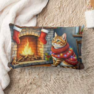 Abessinierkatze sitzt neben dem Kamin mit Weihnach Lendenkissen