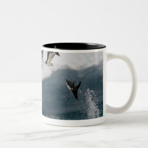 Adelie-Pinguine, die in Meer Paulette tauchen Zweifarbige Tasse