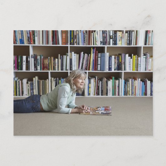 Ältere Frau, die in Bücherregalen liest Postkarte (Vorderseite)