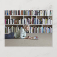 Ältere Frau, die in Bücherregalen liest