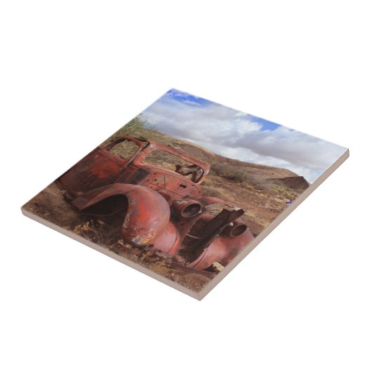 Altes Auto, das in der Wüsten-Landschaft verrostet Fliese (Seite)