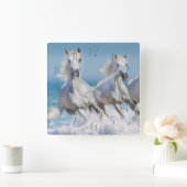 Andalusische weiße Pferde laufen in den Wellen Quadratische Wanduhr (Zuhause)