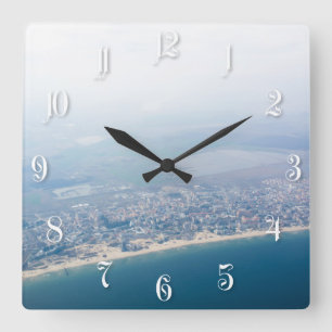 Aussicht auf die Küste durch das Fenster des Flugz Quadratische Wanduhr
