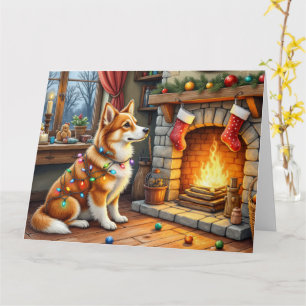Azawakh sitzt neben dem Kamin mit Weihnachtsbeleuc Karte