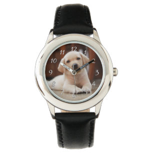 Baby-gelbes Labrador-Hündchen, das auf Bauch legt Armbanduhr