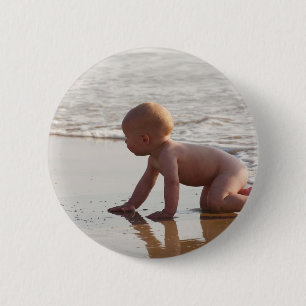 Baby spielt im Sand am Strand Button