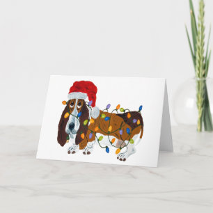 Basset in Weihnachtslichtern verheddert Feiertagskarte