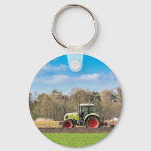 Bauer auf dem Traktor, der sandigen Boden im Schlüsselanhänger