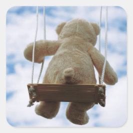 Beertje op schommel met bewolkte blauwe lucht. quadratischer aufkleber