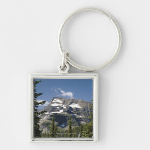 Bergspitze zwischen Bäumen unter einem blauen Schlüsselanhänger
