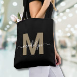 Black Gold Trendy Modern Script Name Monogram Tasche<br><div class="desc">Personalisierte elegante Black Gold Trendy Moderne Skriptname Monogram Tote Bag. Mit dieser schicken Tasche können Sie dem Alltag eine Touch Glamour und Eleganz verleihen. Diese Tasche mit einem eleganten Goldvorschuss (Achtung: das Gold ist flach, ohne Schimmer oder Folie) auf einem knackigen schwarzen Hintergrund zentriert und mit einem sauberen, modernen Design...</div>
