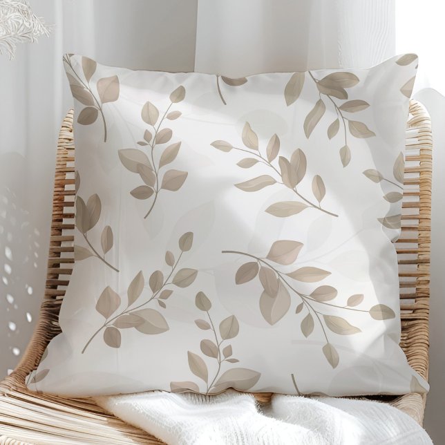 Blätter in Beige und Weiß Kissen (Beige and White Watercolor Leaves Throw Pillow in a sunny rattan armchair.)