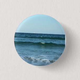 Blaue Wellen, die auf die Küste zurollen Button