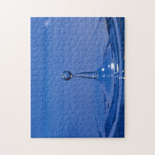 Blauer Wassertropfen in Bewegung auf einem Puzzle (Vertikal)