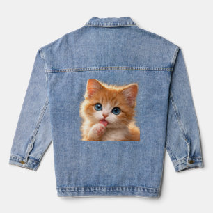 Blaugäugiges Kätzchen leckt Pfote Jeansjacke