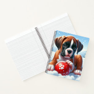 Boxer-Welpe spielt mit einem roten Ball im Winter Notizblock