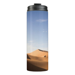 BRAUNER SAND UNTER BLAUEM HIMMEL WÄHREND DES TAGES THERMOSBECHER