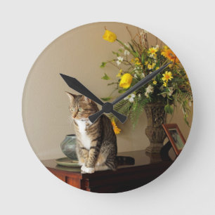 Braunschwarze Tabby-Katze Sitzen auf Klavier-Blume Runde Wanduhr