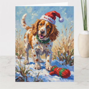 Bretonischer Spaniel zeigt auf Santas Handschuhhut Karte