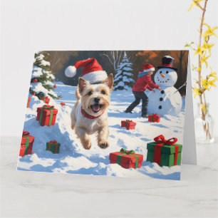 Cairn Terrier läuft im Schnee mit Weihnachtsmütze Karte