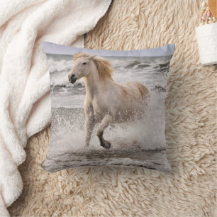 Camargue-Pferd läuft aus der Brandung Kissen