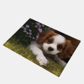 Cavalier King Charles Spanier Welpe hinter Blume Fußmatte (Schrägansicht)