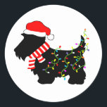 Christmas Scottie Dog mit Licht Runder Aufkleber<br><div class="desc">Schottische Hundeliebhaber von Terrier werden diesen festlichen,  schwarzen Scottie Dog mit einer Weihnachtsmannmütze,  rot-weiß gestreiften Schal und bunten Saitenleuchten genießen! Erleben Sie den Weihnachtsgeist mit diesem lustigen Design auf anpassbaren Geschenken!</div>