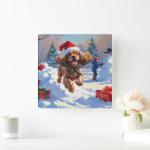 Cocker Spaniel läuft in Schnee mit Weihnachtshut Quadratische Wanduhr (Zuhause)