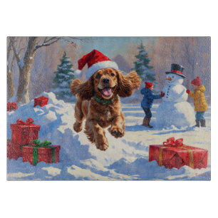 Cocker Spaniel läuft in Schnee mit Weihnachtshut Schneidebrett