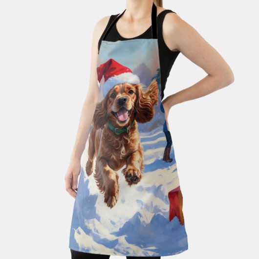 Cocker Spaniel läuft in Schnee mit Weihnachtshut Schürze (InSitu)