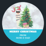 Cooler Llama auf Silver Bokeh & Icy Blue Christmas Runder Aufkleber<br><div class="desc">Weihnachtsaufkleber personalisiert mit Ihrem Namen. Erstellt mit einer lustigen Illustration. Ein niedliches Lamm mit schwarzer Sonnenbrille und einer roten Weihnachtsmannmütze. Stehend hinter einem Weihnachtsbaum mit festlichen Geschenken. Das Wort Joy schrieb über seinem Kopf in einem bunten Schriftart. Silver Bukh Hintergrund mit einem eisblauen Rand. Whimsical und Spaß Weihnachten Thema Design....</div>