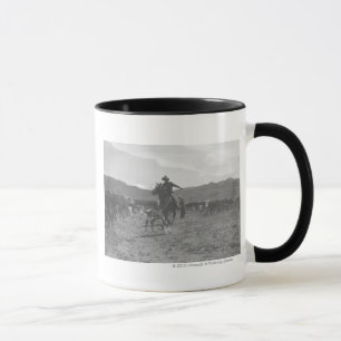 Cowboy, der ein Kalb für das Frühlingseinbrennen Tasse
