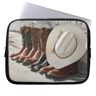 Cowboy-Hut in Reihe von Cowboy-Stiefeln außerhalb Laptopschutzhülle