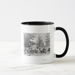 Cowboys, die Abendessen auf dem Boden unter Bäumen Tasse