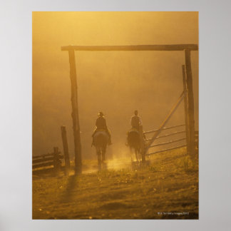 Cowboys fahren bei Dämmerung durch Tor Poster