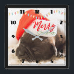 Cute Pug in a Red Santa Hat Merry Christmas Quadratische Wanduhr<br><div class="desc">A clock with an adorable photo of a pug puppy sleeping while wearing a red santa hat. Merry Christmas is written on the band of his hat,  in a trendy handwritten font,  in the festive colors red and green. Christmas lights strung across the top creates additional seasonal holiday flair.</div>