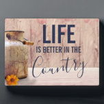 Das Leben ist besser im Land Zitat mit Milch kann Fotoplatte<br><div class="desc">Eine Foto-Plakette mit rustikalem Landdesign. Eine trendige alte rostende Milch kann. Weiße und verblasste rote Pupien im Hintergrund Set vor einem schwachen Holzpaneel. Holz ist nur ein Bild,  nicht real. Im Text steht,  dass das Leben im Land besser ist.</div>