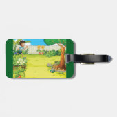 Der spielerische Junge, der in einem üppig grünen  Gepäckanhänger (Rückseite horizontal)