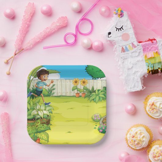 Der spielerische Junge, der in einem üppig grünen  Pappteller (Party)