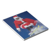 Der Weihnachtsmann auf Skiern springt von einem Ko Notizblock (angewinkelt)