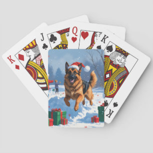 Deutscher Schäferhund läuft im Schnee mit Weihnach Spielkarten