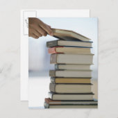 Die Hand des Mannes, die ein Buch von einem Stapel Postkarte (Vorne/Hinten)