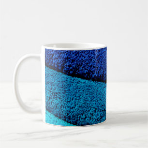 Die Handtücher sind blau, türkisblau und grau Kaffeetasse