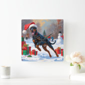 Doberman läuft im Schnee mit Weihnachtshut Quadratische Wanduhr (Zuhause)