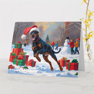 Dobermann läuft im Schnee mit Weihnachtsmütze Karte