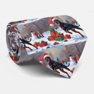 Dobermann läuft im Schnee mit Weihnachtsmütze Krawatte