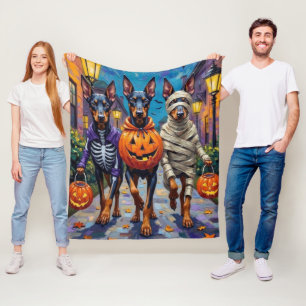 Dobermänner in Halloween-Kostümen beim Süßigkeiten Fleecedecke