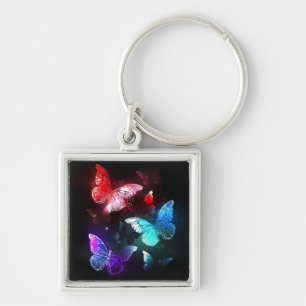 Drei glühende Schmetterlinge im Hintergrund Schlüsselanhänger